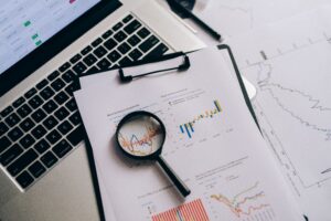 Magnifying glass over financial charts representing red flags to catch in a monthly owner report